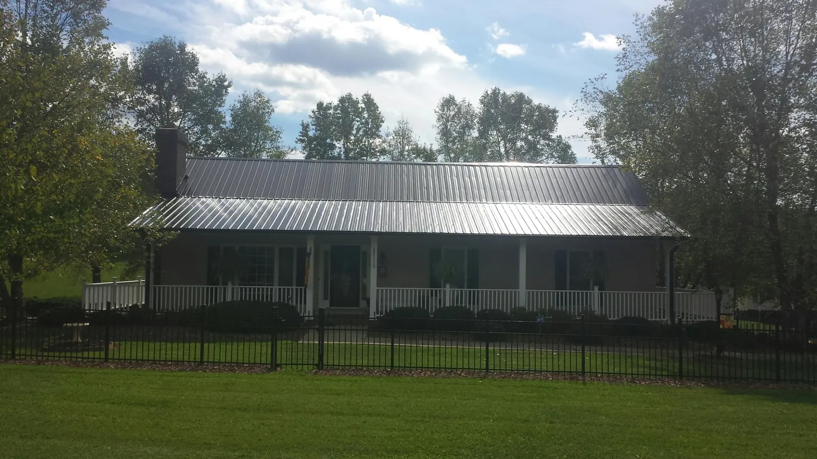 Gray metal roof on a brick ranch with a full width front porch — Gutter Guard Installation work by our crew in Hopkins