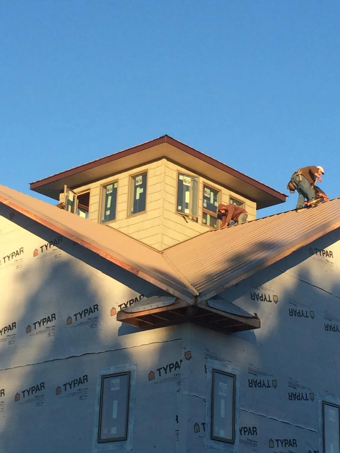 Roofers working around a rooftop cupola on a new metal roof at sunset — Roof Waterproofing in Hopkins by Roofing Brothers